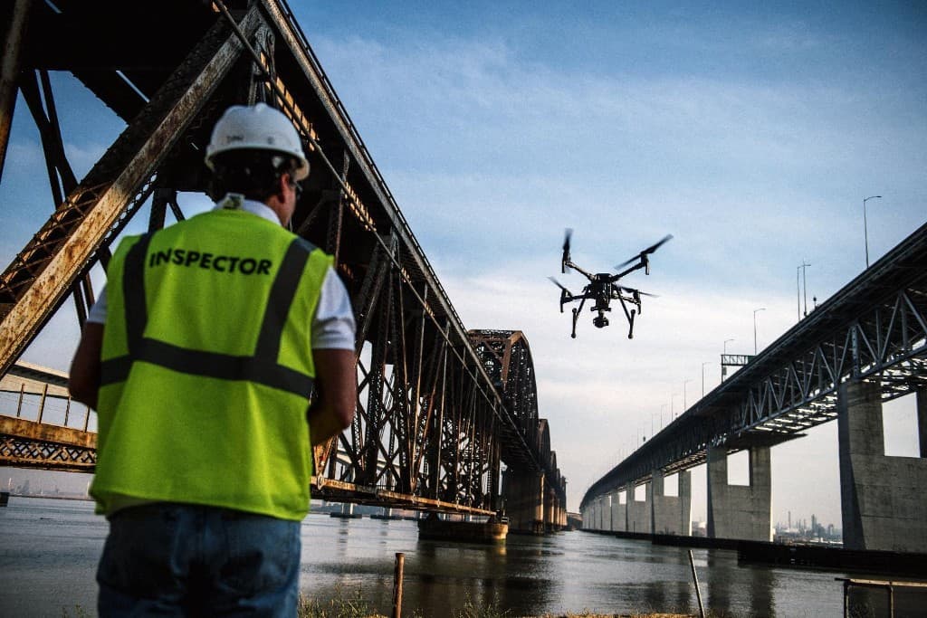 Inspector operating a drone to inspect bridges and critical infrastructure over water